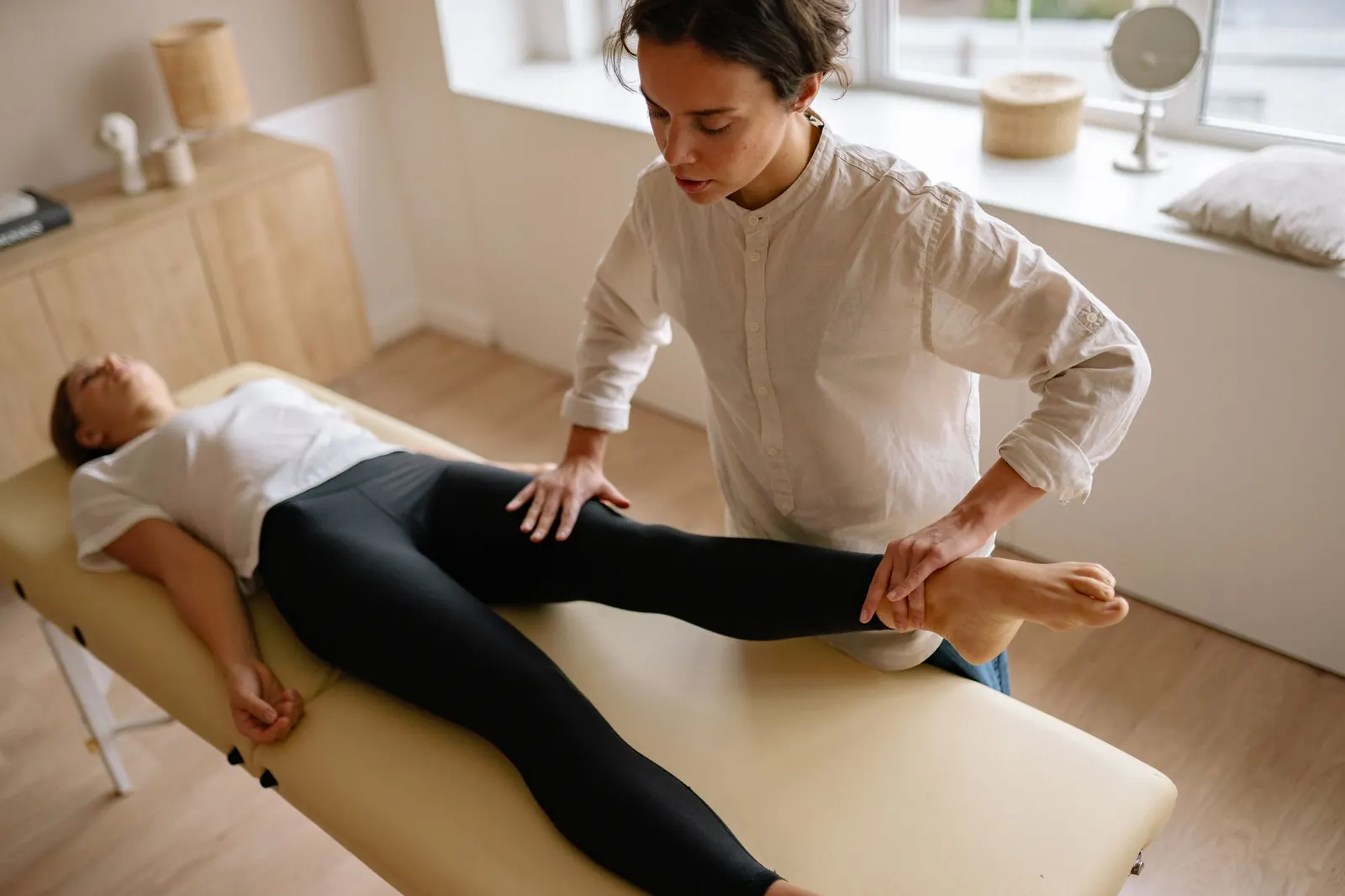 Therapist giving hands-on leg treatment to a patient on a couch